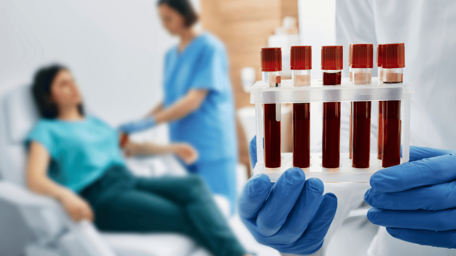 Close-up of a healthcare professional holding blood samples in test tubes, with a patient 